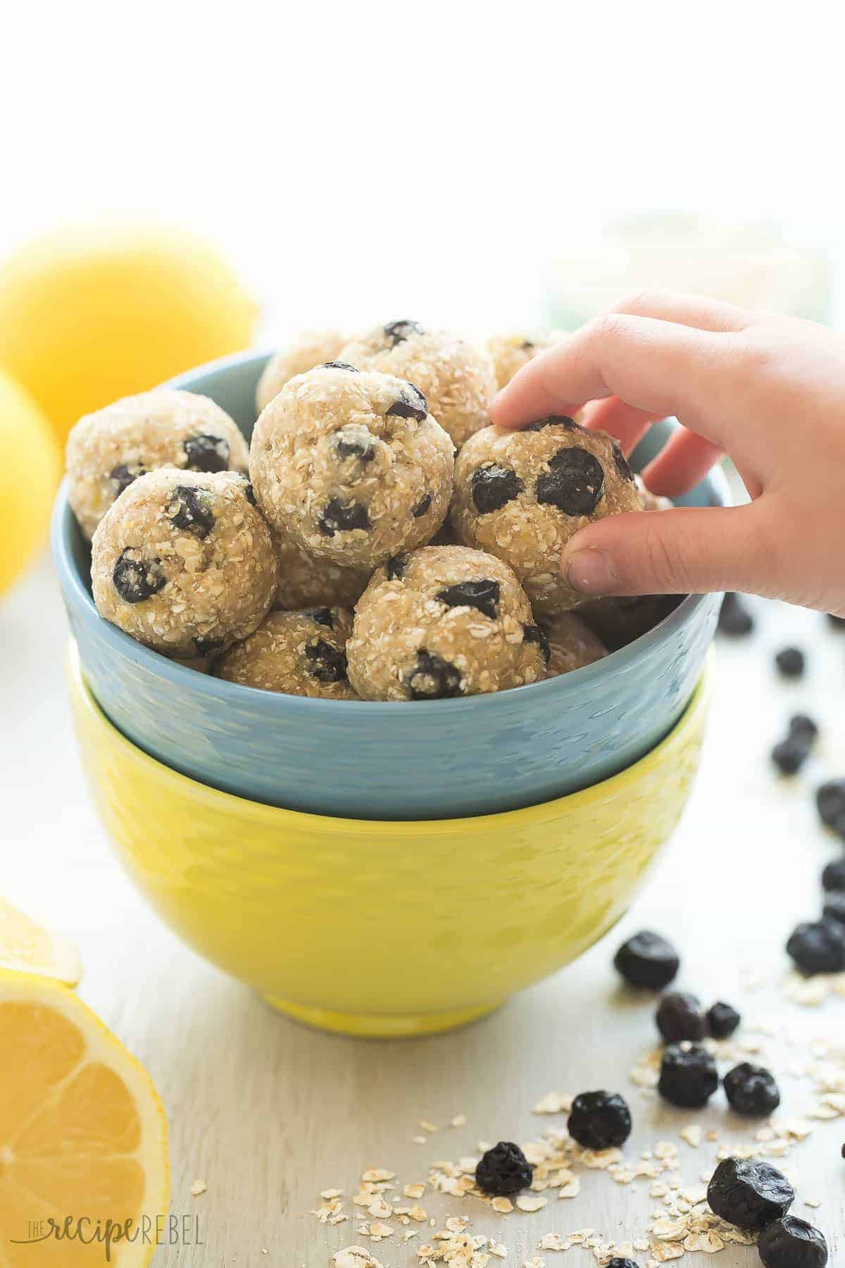 childs hand grabbing a lemon blueberry energy bite from blue bowl