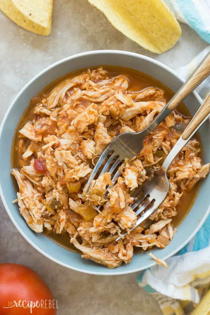 slow cooker mango salsa chicken shredded in a blue bowl with two forks