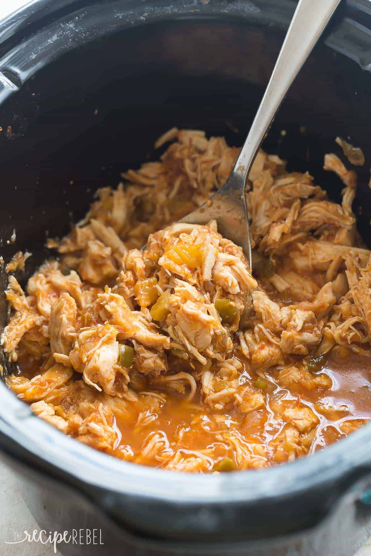 mango salsa chicken shredded in black slow cooker with metal scoop