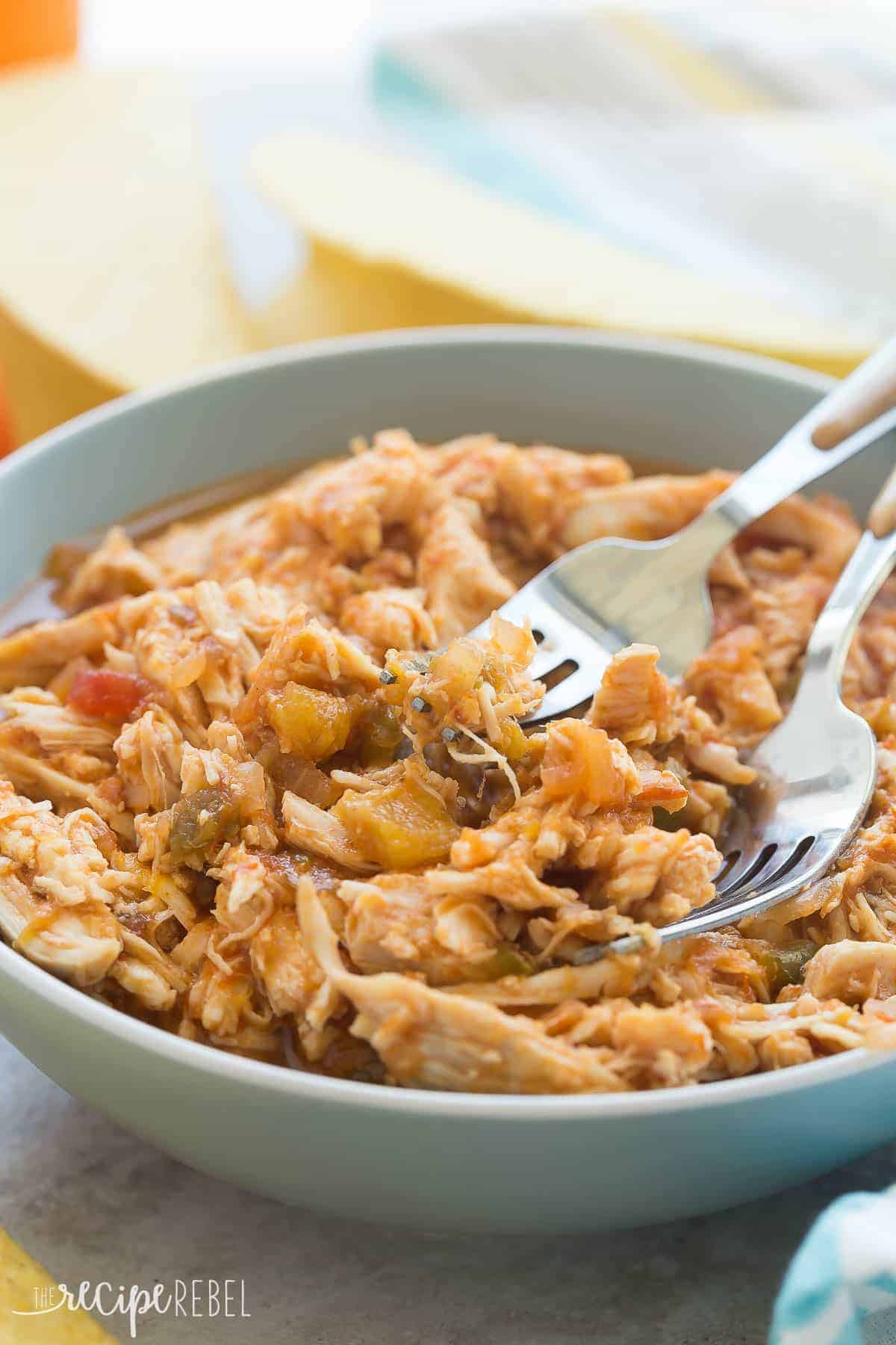 close up of slow cooker mango salsa chicken in blue bowl with two forks