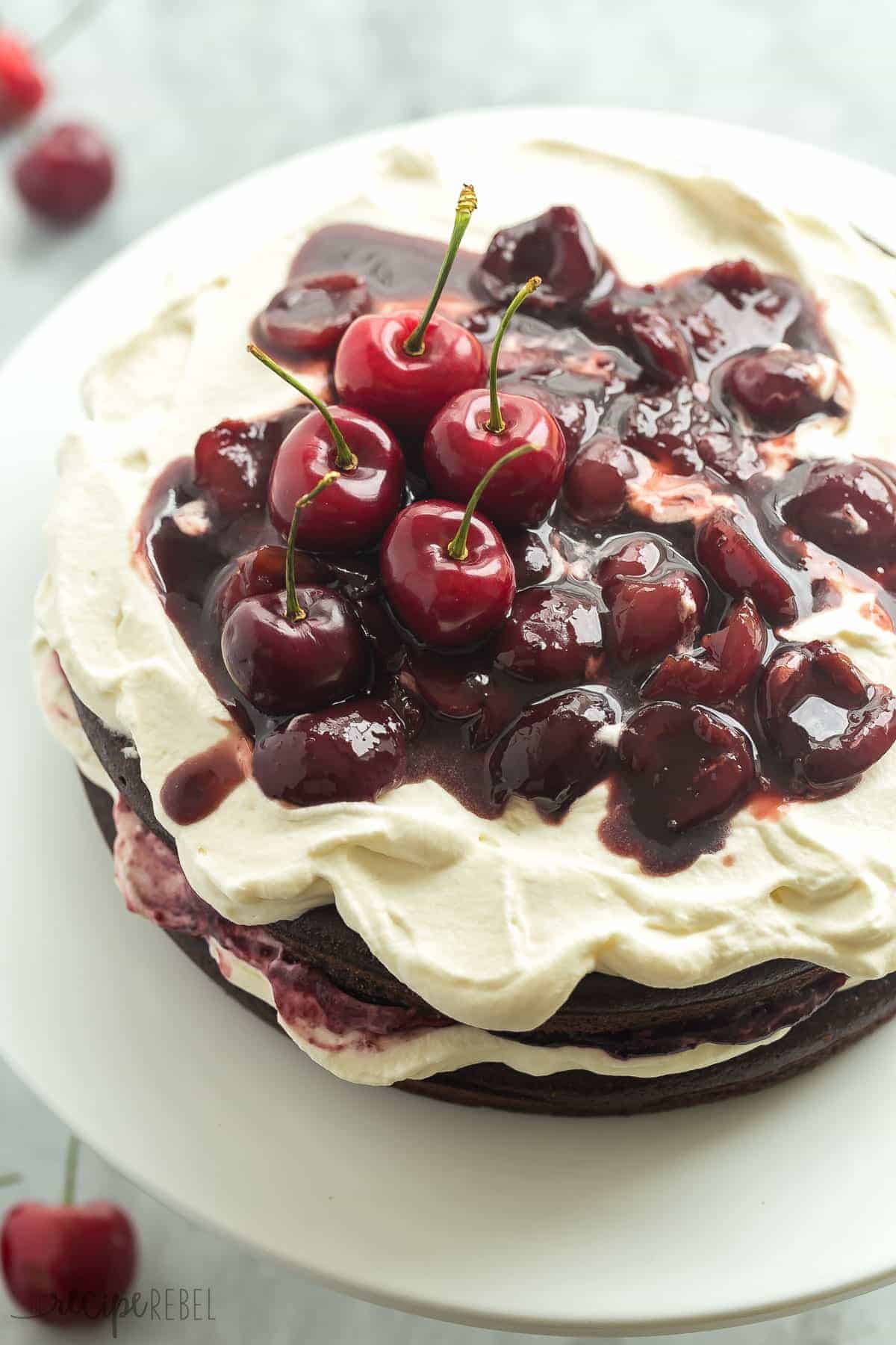 gluten free black forest cake whole with whipped cream and fresh dark cherry sauce