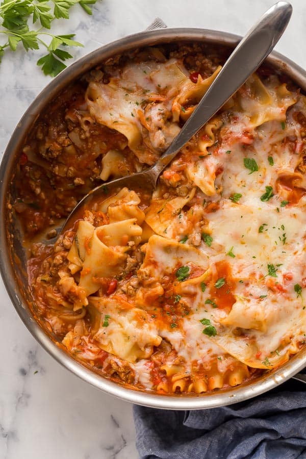 spoon scooping skillet lasagna from pan