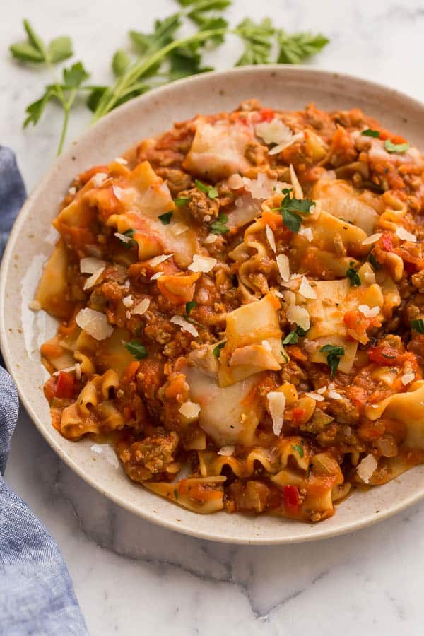 skillet lasagna on plate topped with parsley and cheese