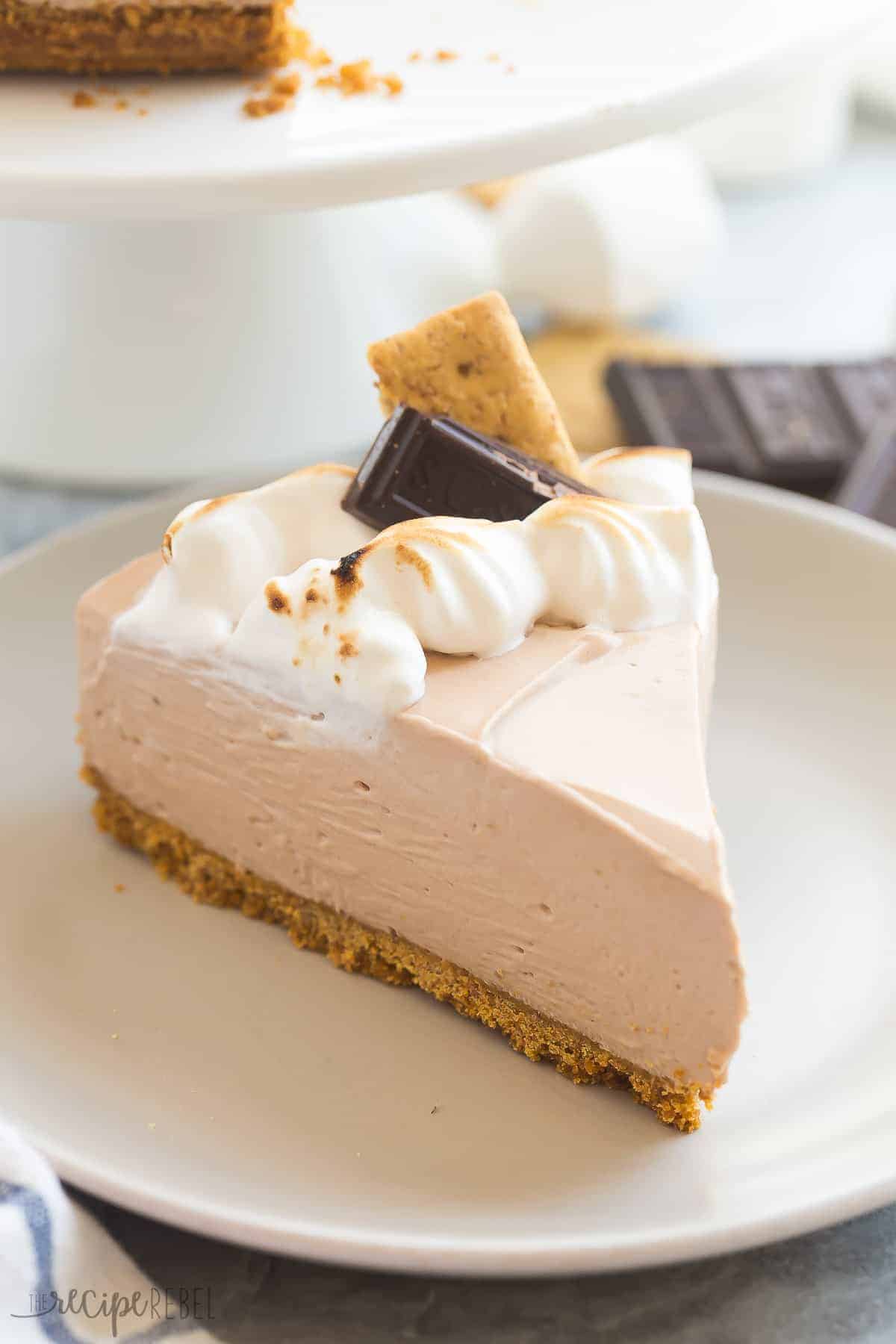 slice of no bake smores cheesecake on grey plate with toasted marshmallow creme chocolate chunk and graham cracker