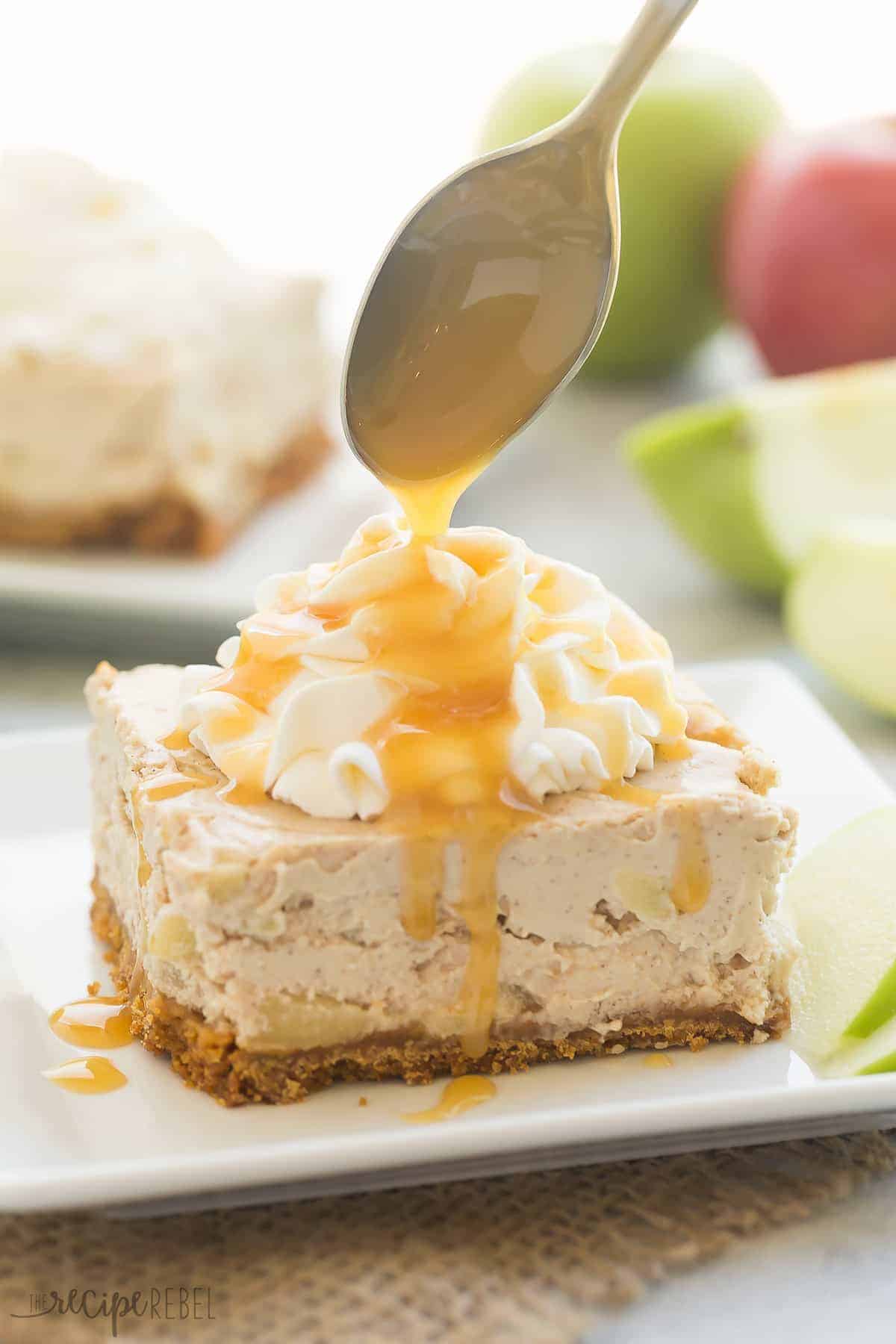 caramel apple cheesecake bars slice on white plate with caramel drizzle and apples in the background