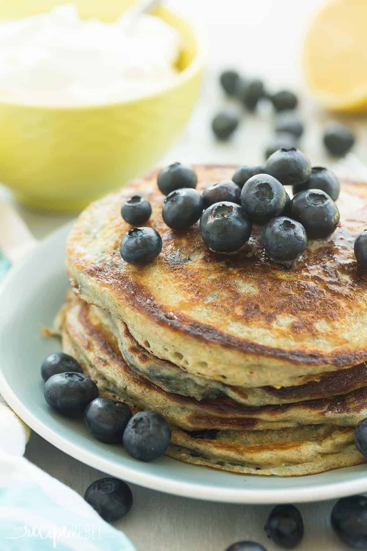 stack of lemon blueberry greek yogurt pancakes on blue plate with fresh blueberries