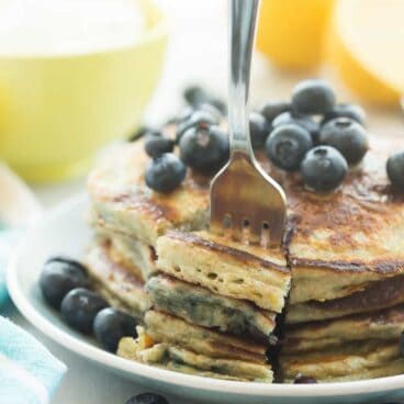 These Lemon Blueberry Greek Yogurt Pancakes are light, fluffy and made healthier with whole wheat flour! They're loaded with blueberries and pack a punch of citrus flavor!