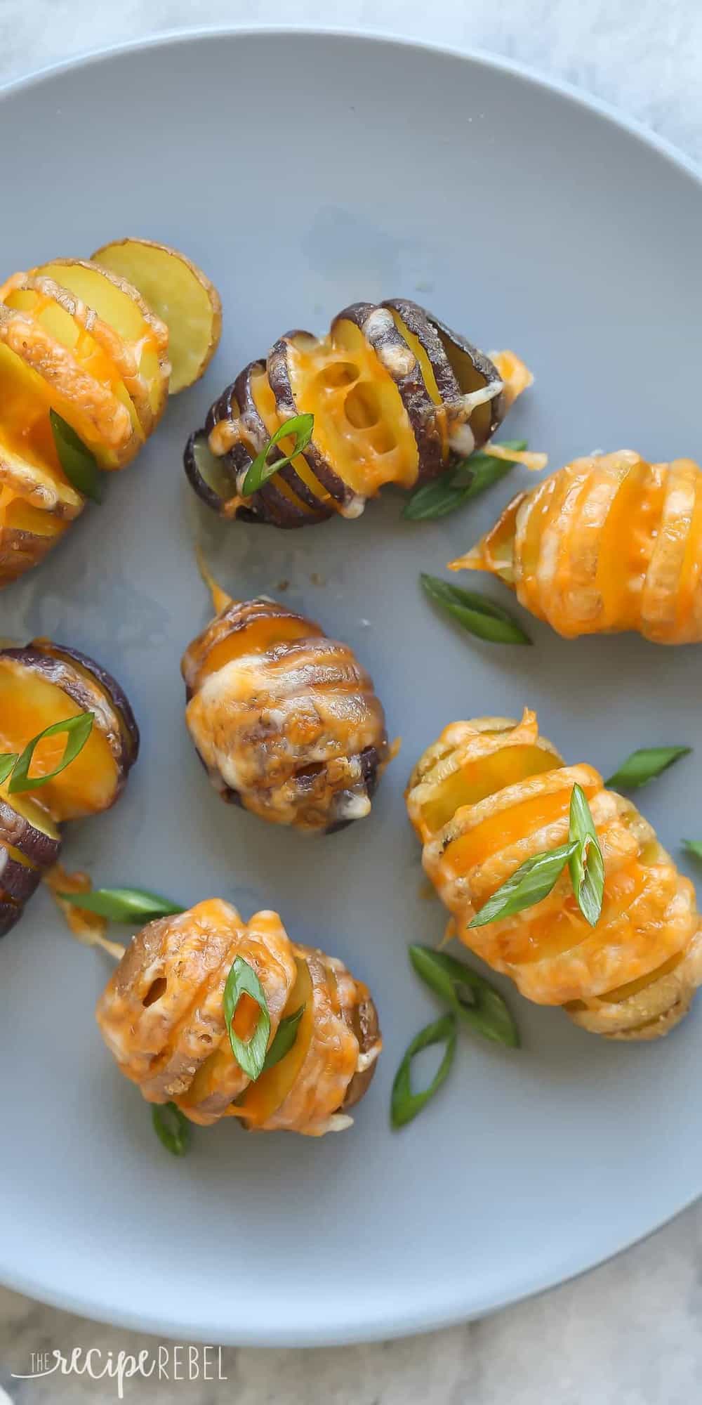 little cheesy hasselback potatoes overhead on grey plate with green onions