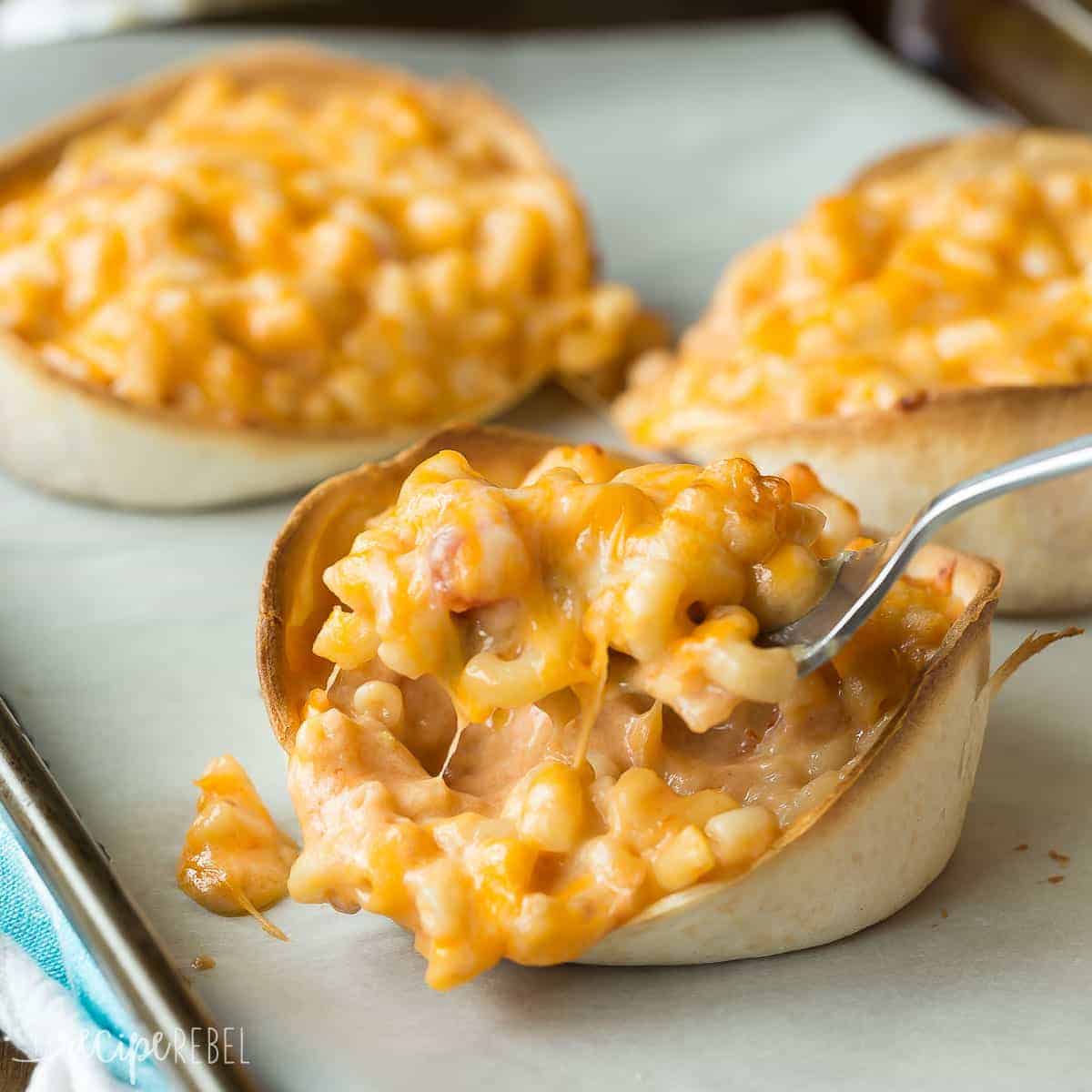 tortilla bowls filled with mac and cheese and fork scooping mac and cheese