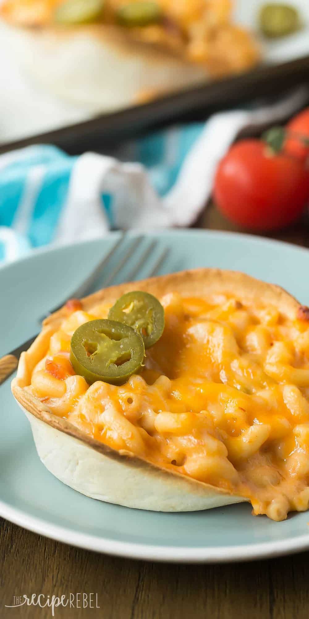 tall image of close up of one tortilla bowl with mexican mac and cheese inside topped with jalapenos