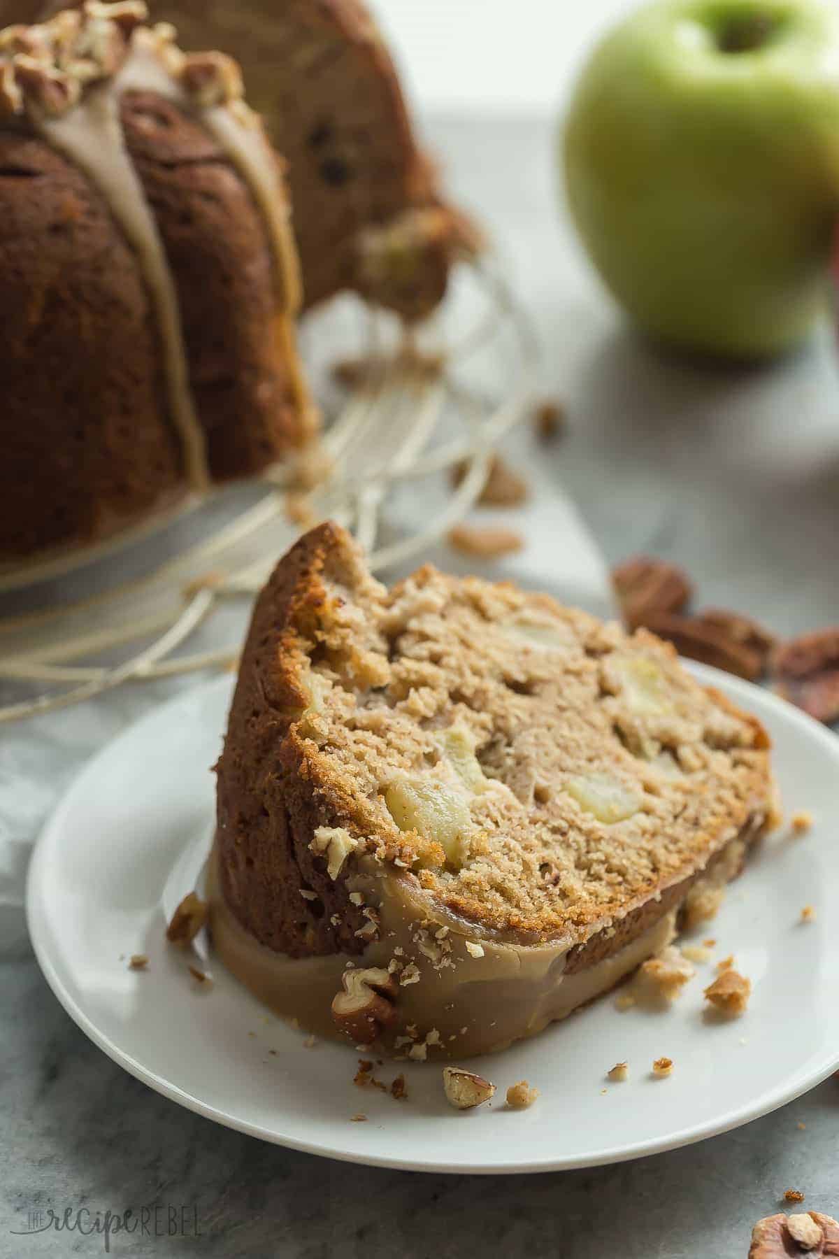 slice of apple bundt cake on white plate with caramel glaze and chopped pecans