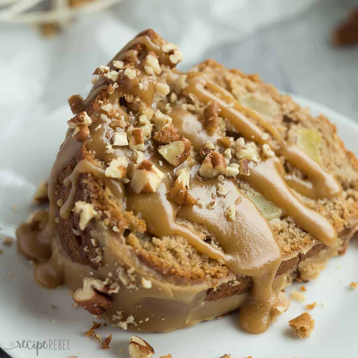 slice of apple bundt cake on plate with extra praline glaze and chopped pecans