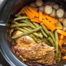 black crockpot with slow cooker peanut chicken and vegetables in it