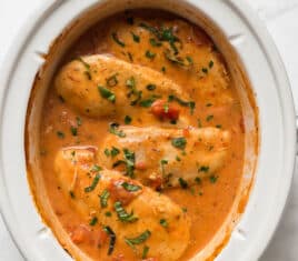 slow cooker creamy tomato basil chicken in a white crockpot