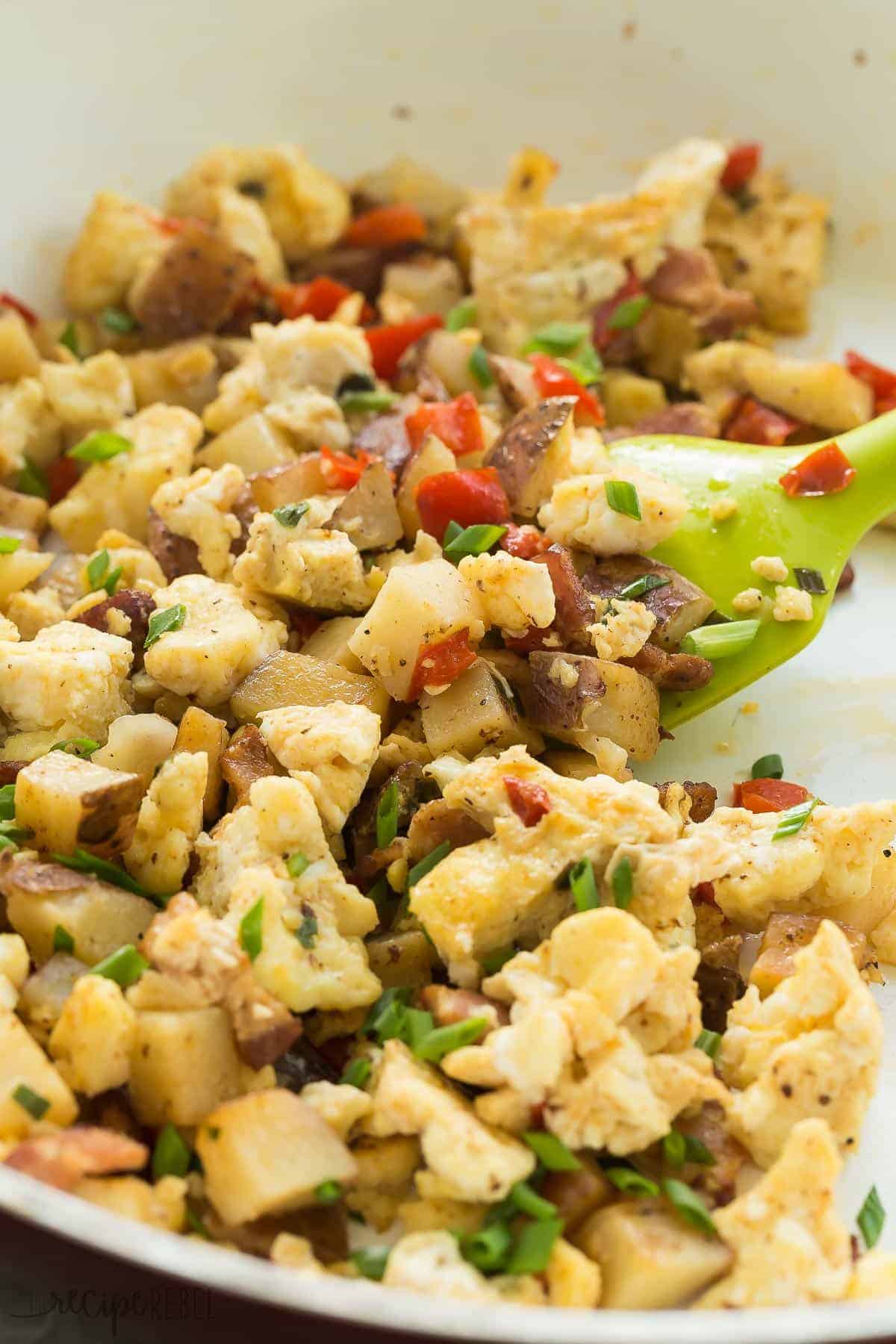 close up of scrambled eggs made for breakfast burritos with green onions peppers and bacon