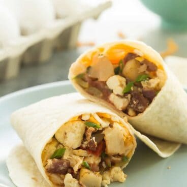 These are our FAVORITE Breakfast Burritos! They are loaded with homemade hashbrowns, peppers, bacon, eggs, salsa and cheese! They are make ahead and freezer friendly -- perfect for busy weeknights.
