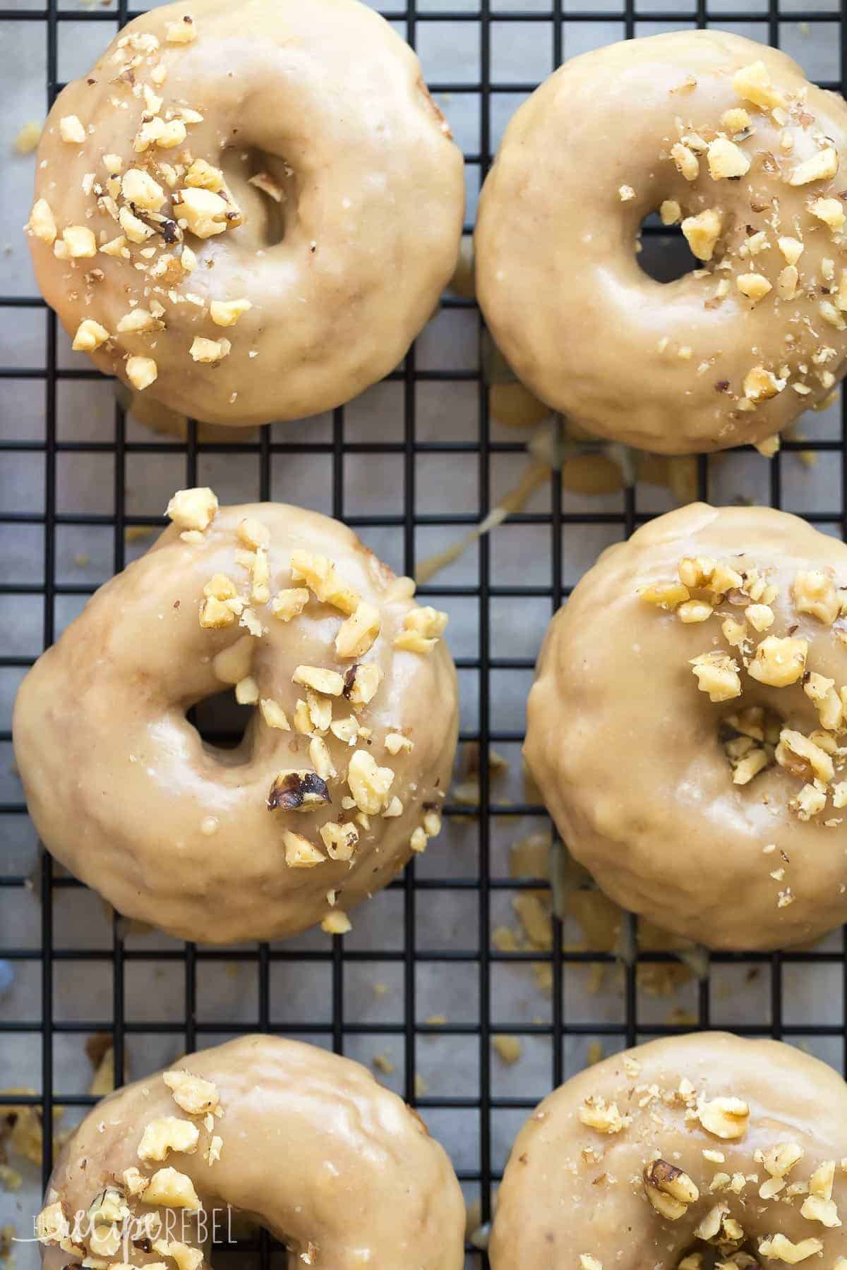 overhead close up image of 6 baked apple donuts on black cooling rack