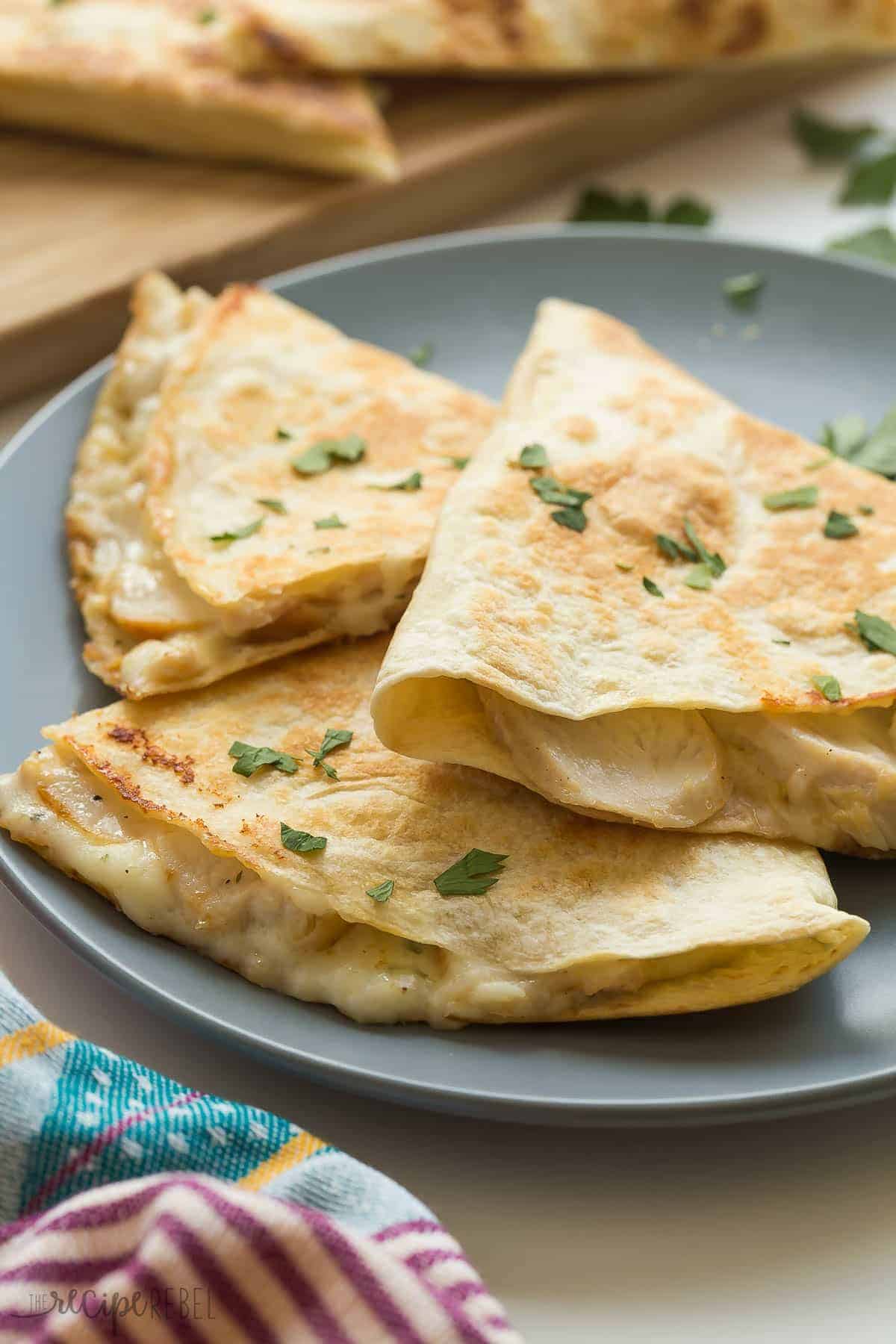 grey plate with three wedges of chicken alfredo quessadillas