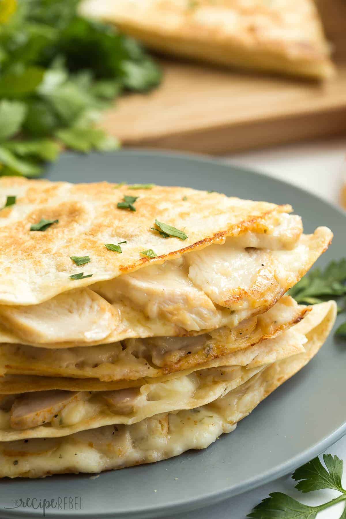 stack of chicken alfredo quesadillas on grey plate sprinkled with fresh parsley