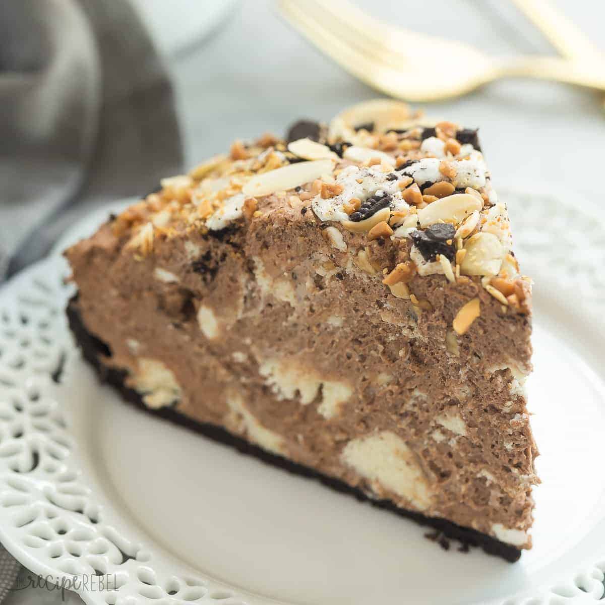 square image of chocolate explosion slice on white plate with oreos almonds and toffee bits