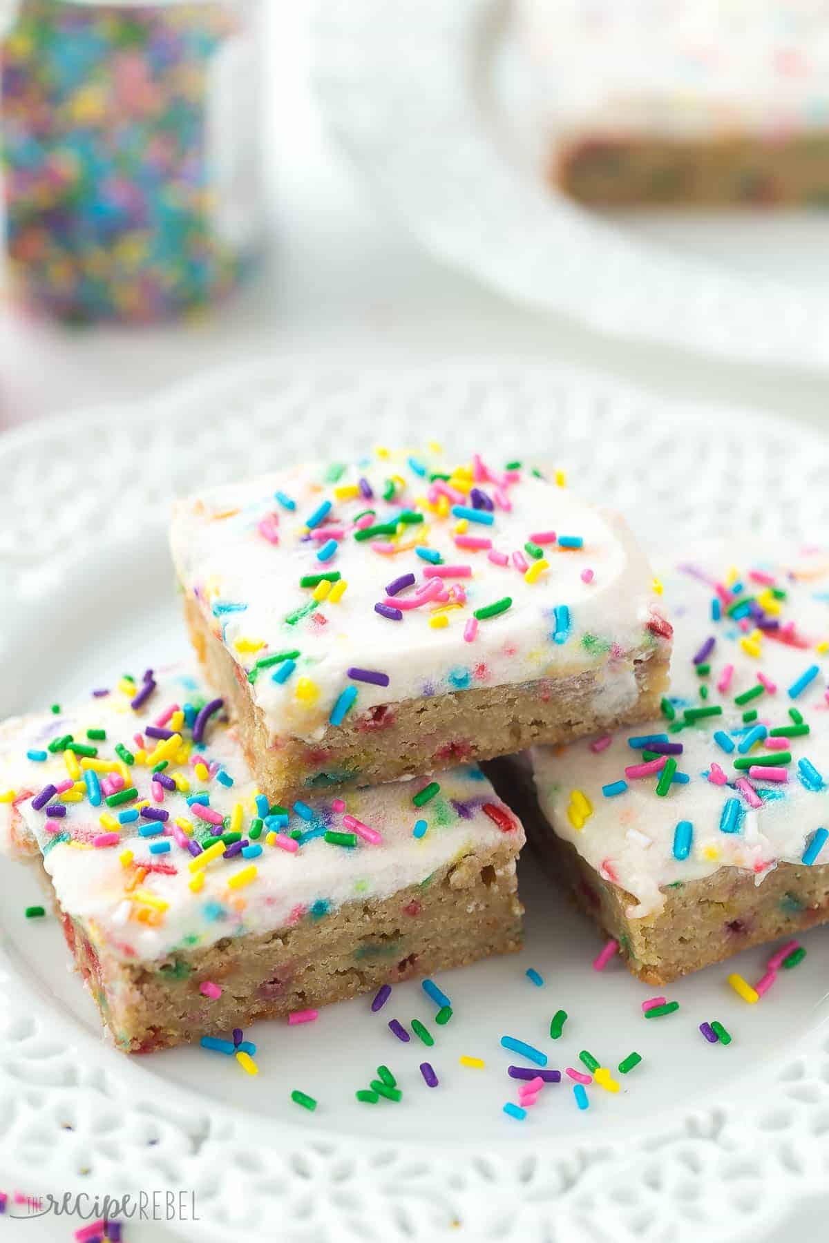 white plate with stack of 3 funfetti blondies with frosting and sprinkles