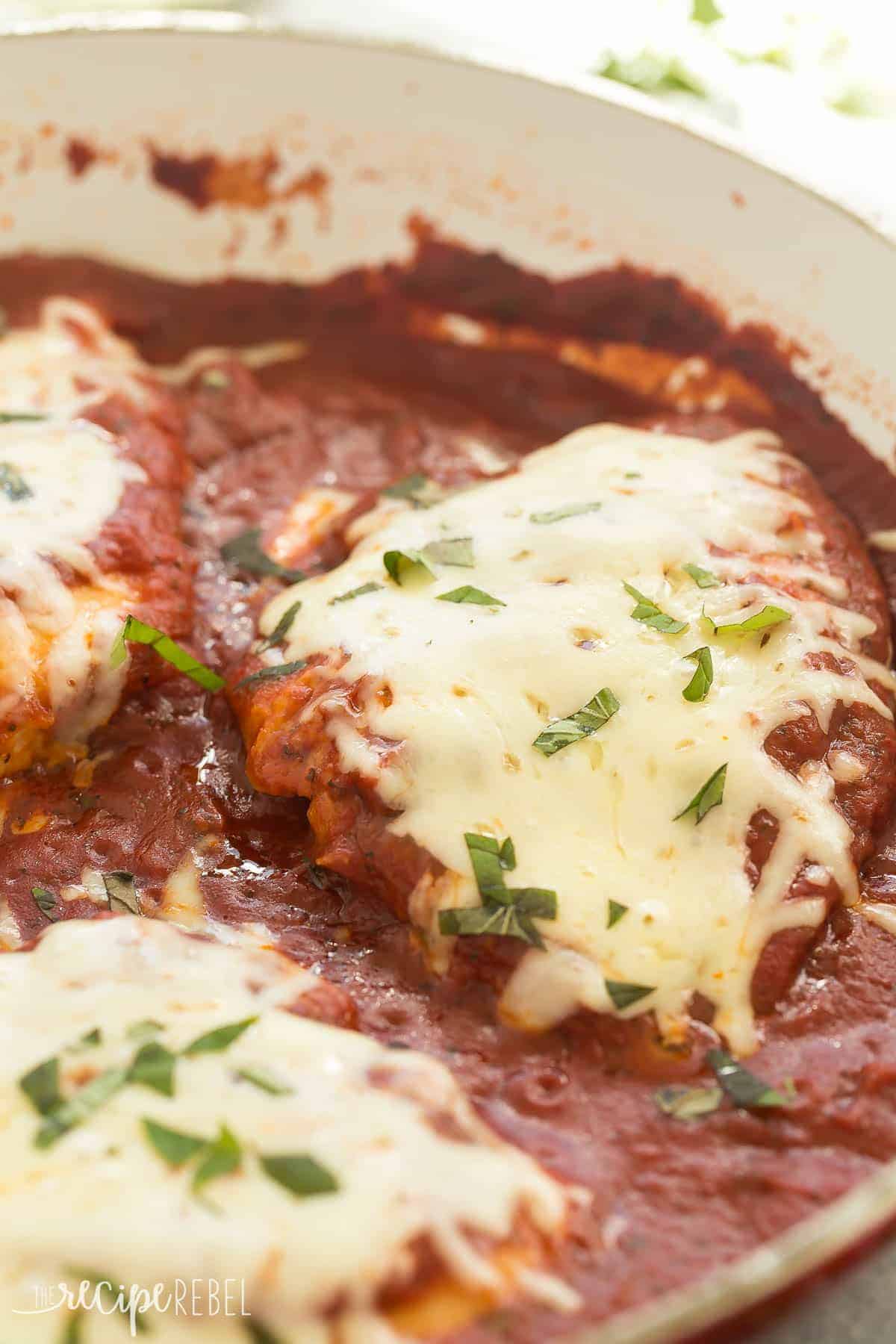 close up image of skillet chicken parmesan with mozzarella cheese and fresh parsley
