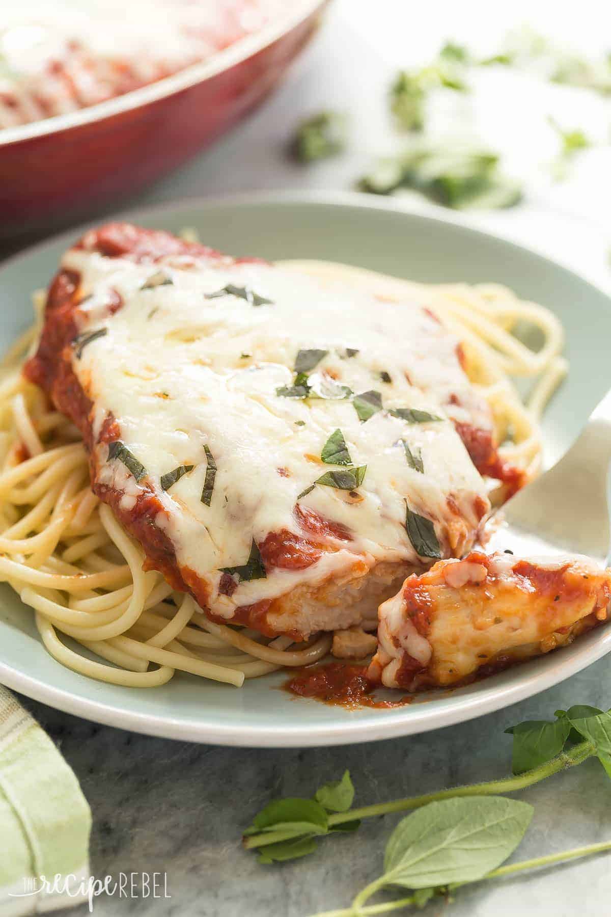 skillet chicken parmesan with melted cheese on a bed of spaghetti