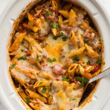 overhead image of slow cooker baked ziti in white crockpot.