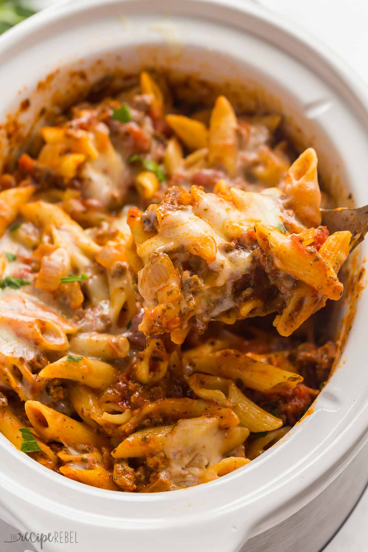 spoon scooping crockpot baked ziit out of slow cooker.