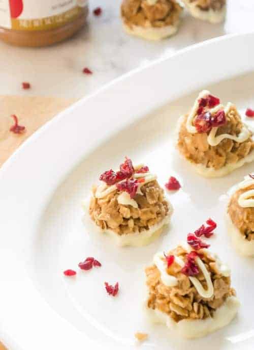 no bake white chocolate biscoff oatmeal cookies on white platter with dried cranberries on top