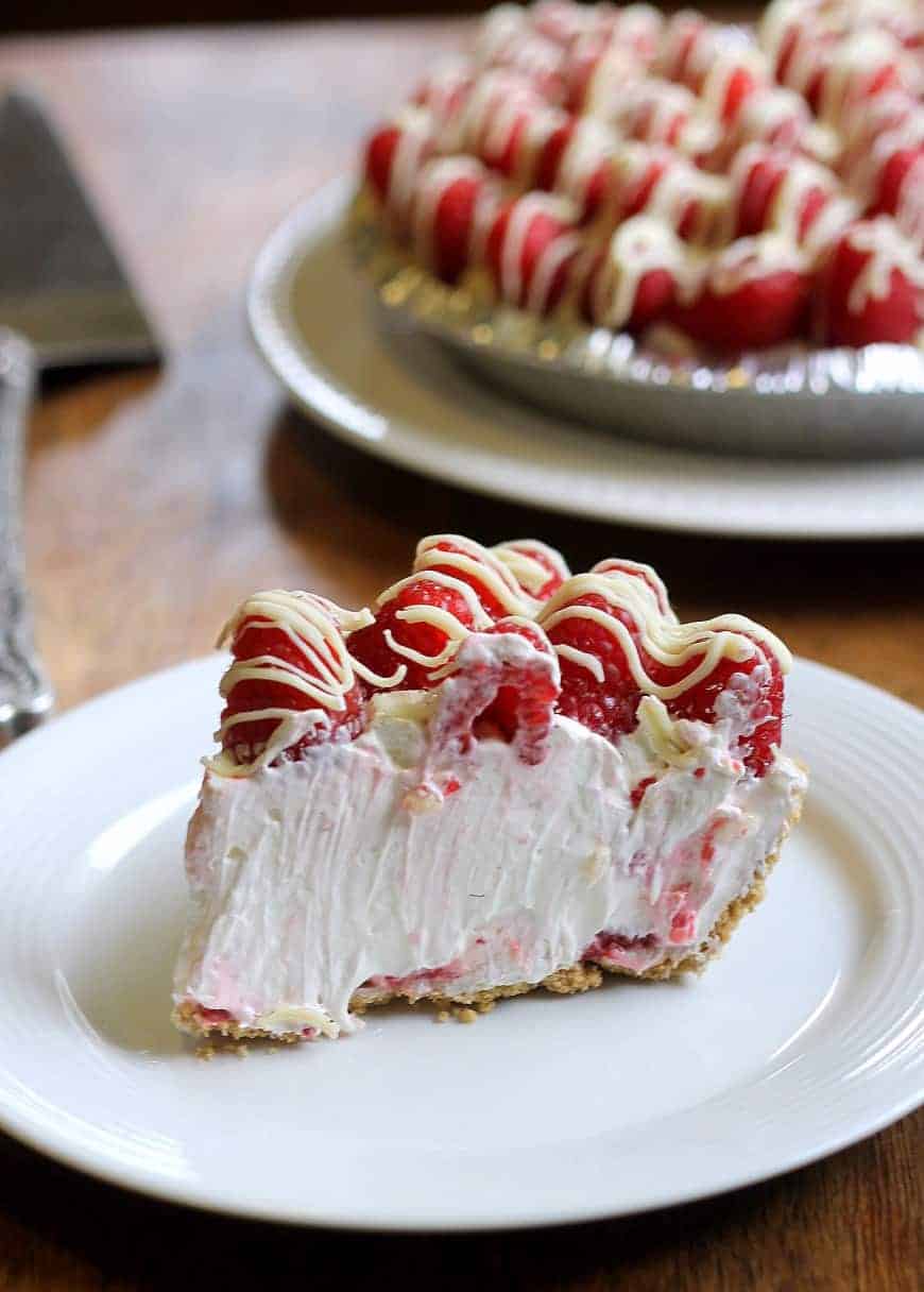 white chocolate cheesecake pie with raspberries on top on a white plate