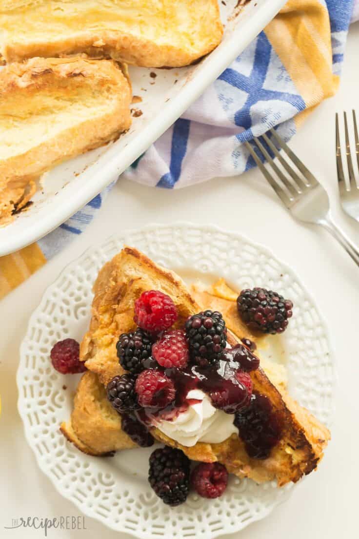 overnight lemon french toast on white plate with berries and whipped cream overhead
