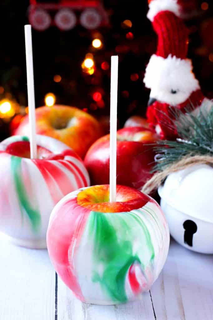 christmas marbled dipped apples with white sticks and christmas decor in the background
