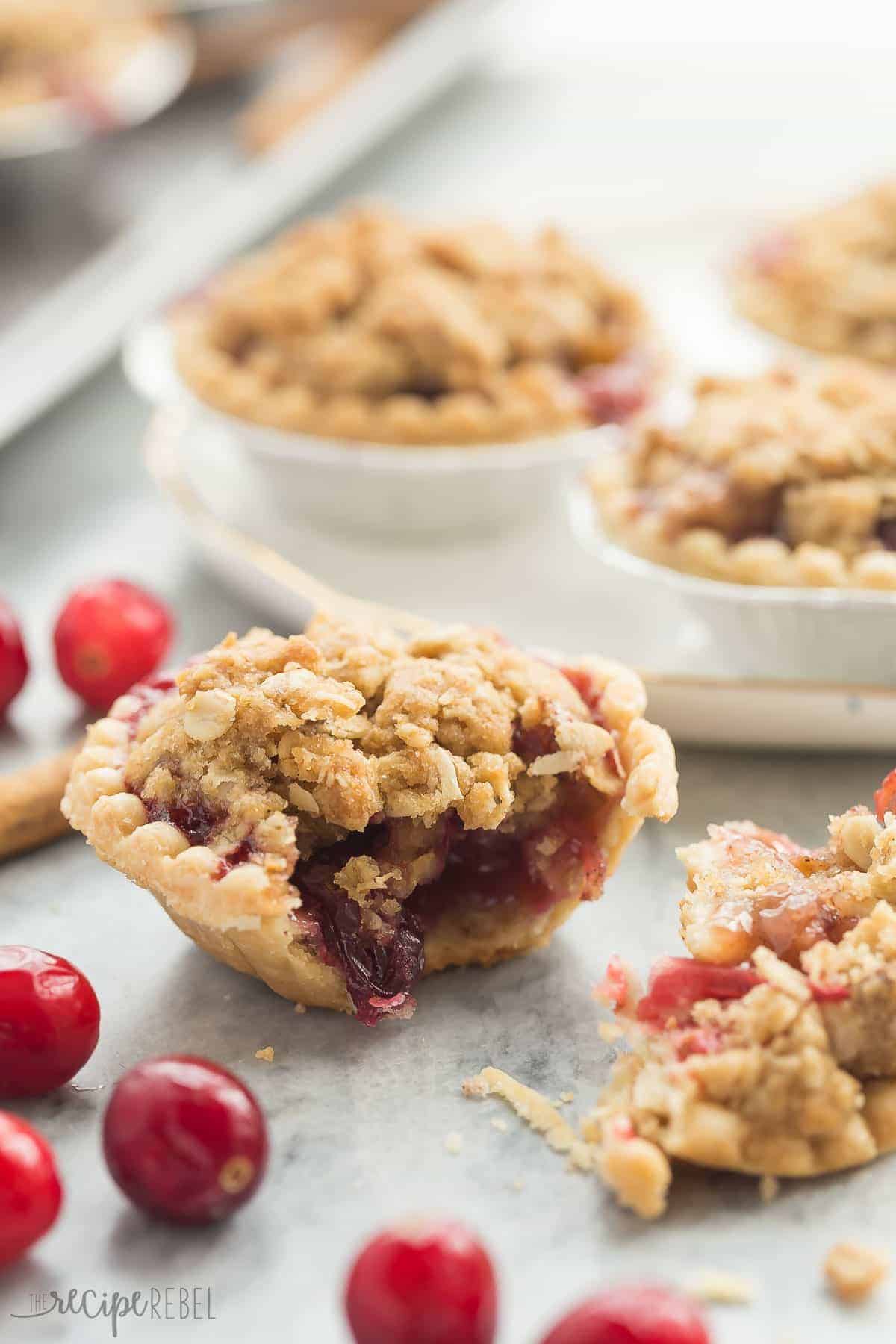 mini cranberry apple pie on marble broken in half with fresh cranberries on the side