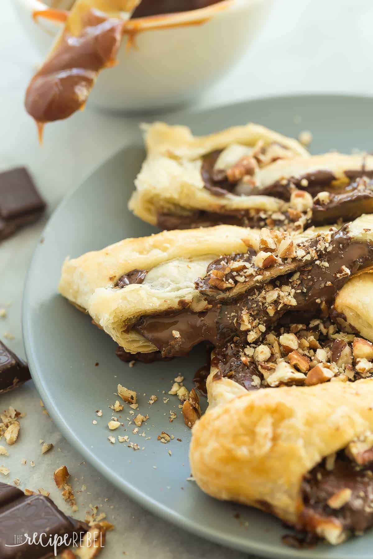 This Easy Turtle Danish is full of chocolate, caramel and pecans! Only a few ingredients but looks so impressive! An easy dessert or special brunch idea! slices of turtle danish on grey plate with chopped pecans and chocolate pieces