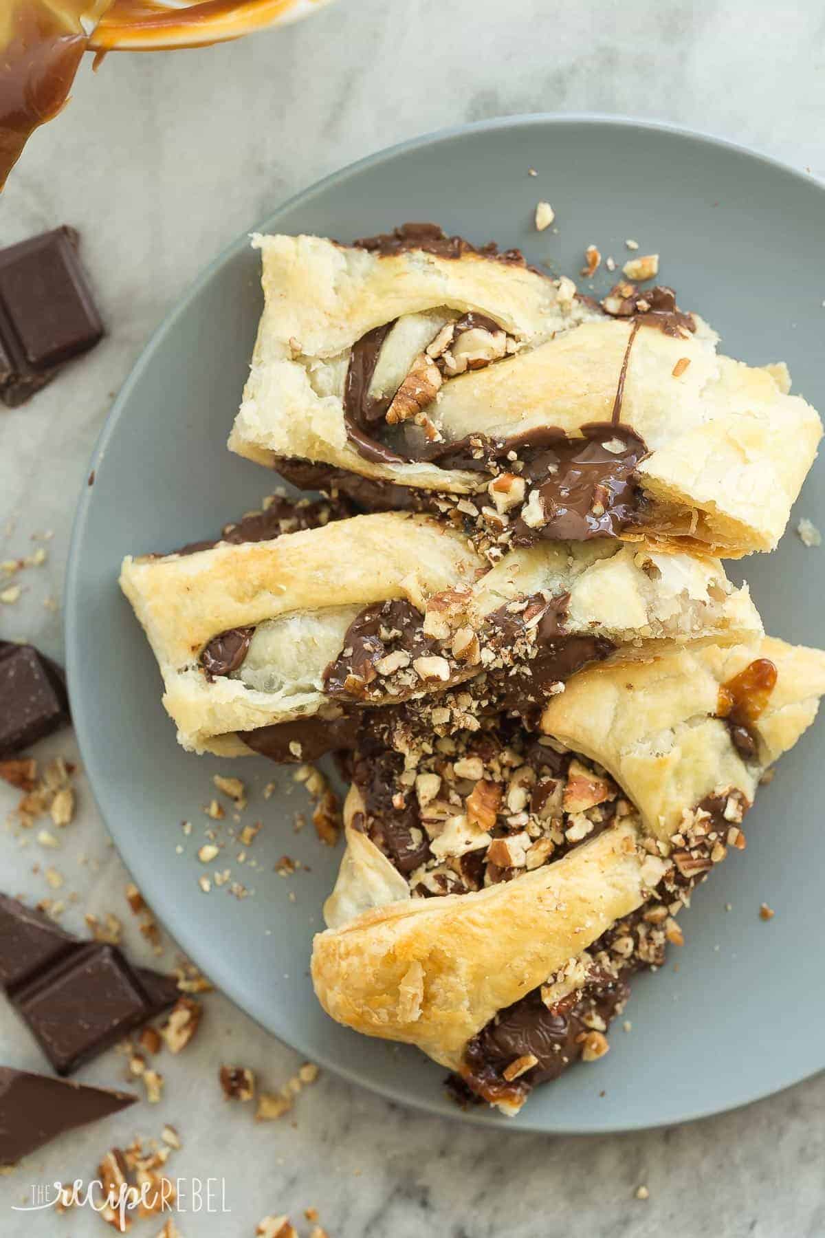 three slices of turtle puff pastry danish on grey plate with chopped pecans