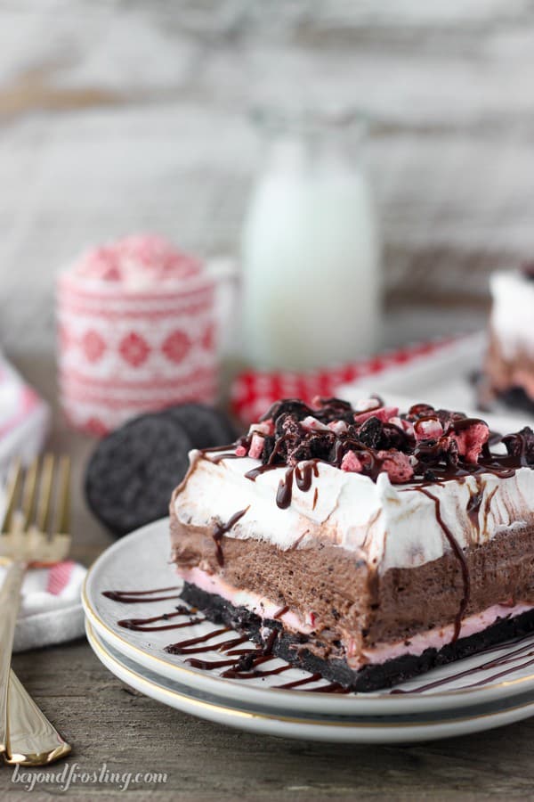 no bake peppermint oreo lush on two stacked plates with christmas decor in the background and glass of milk