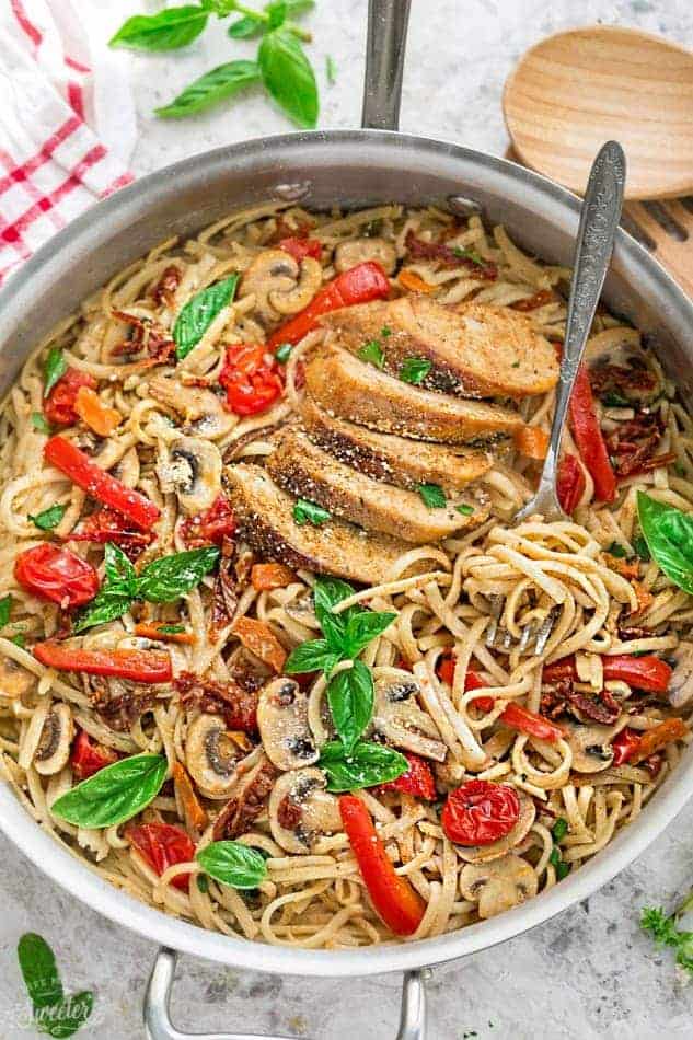 stainless steel pan with linguine and sliced chicken breast peppers tomato and basil