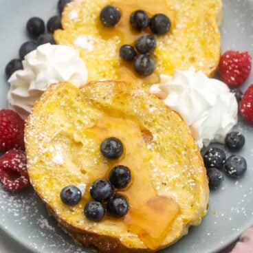 close up image of lemon french toast on a plate with blueberries and whipped cream.