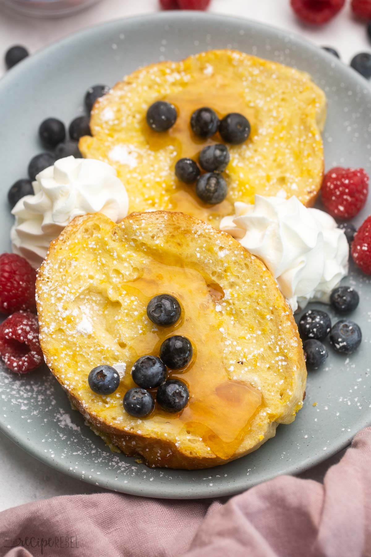 close up image of lemon french toast on a plate with blueberries and whipped cream.