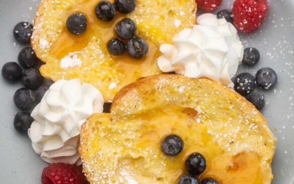overhead image of baked lemon french toast with blueberries and raspberries.