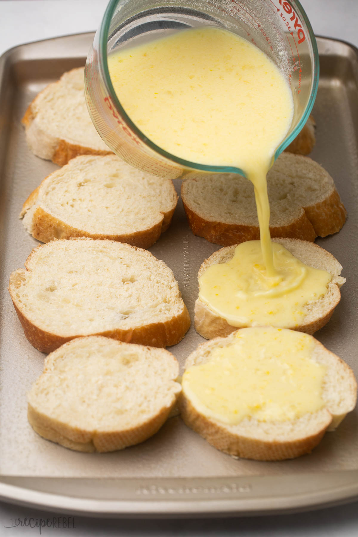 pouring egg mixture on french bread to make french toast.