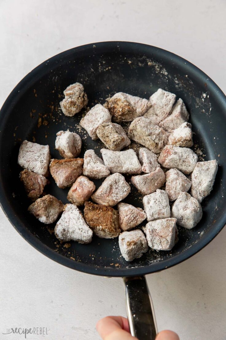 corn starch coated beef cubes in frying pan