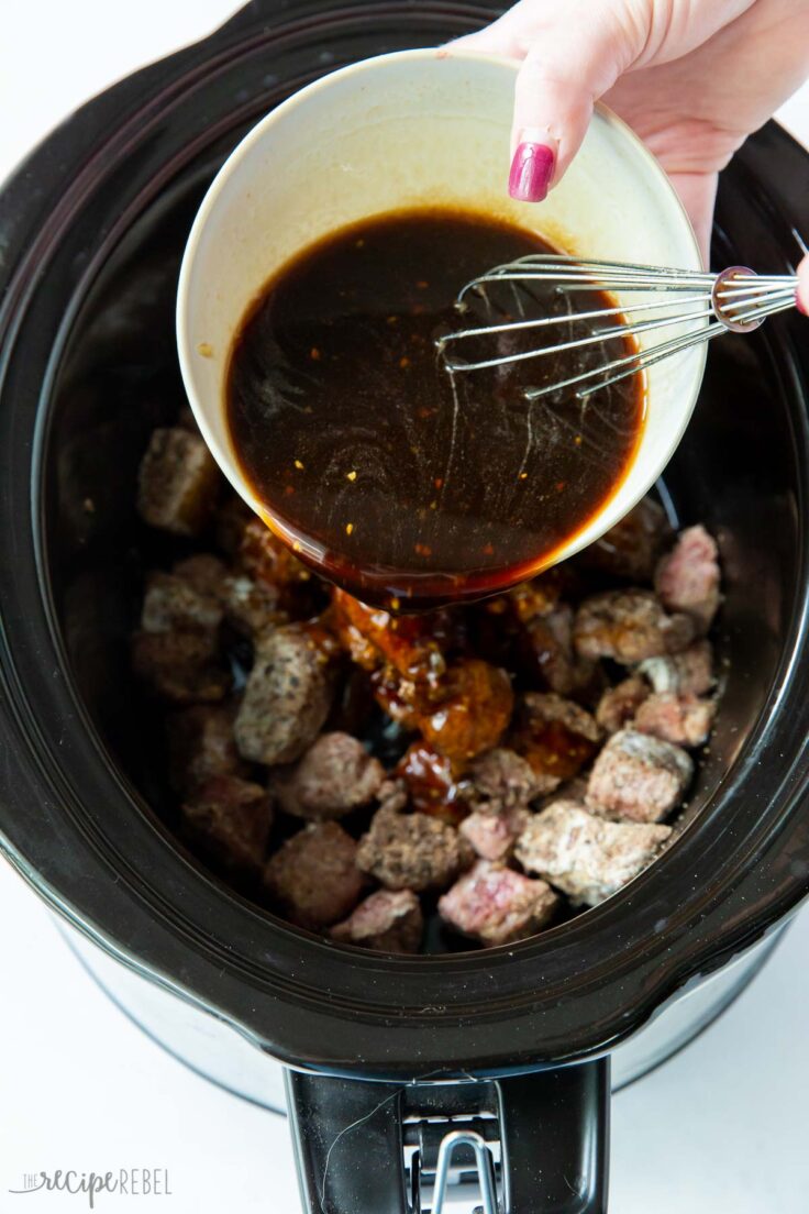 cubes of beef in slow cooker with sauce going on top