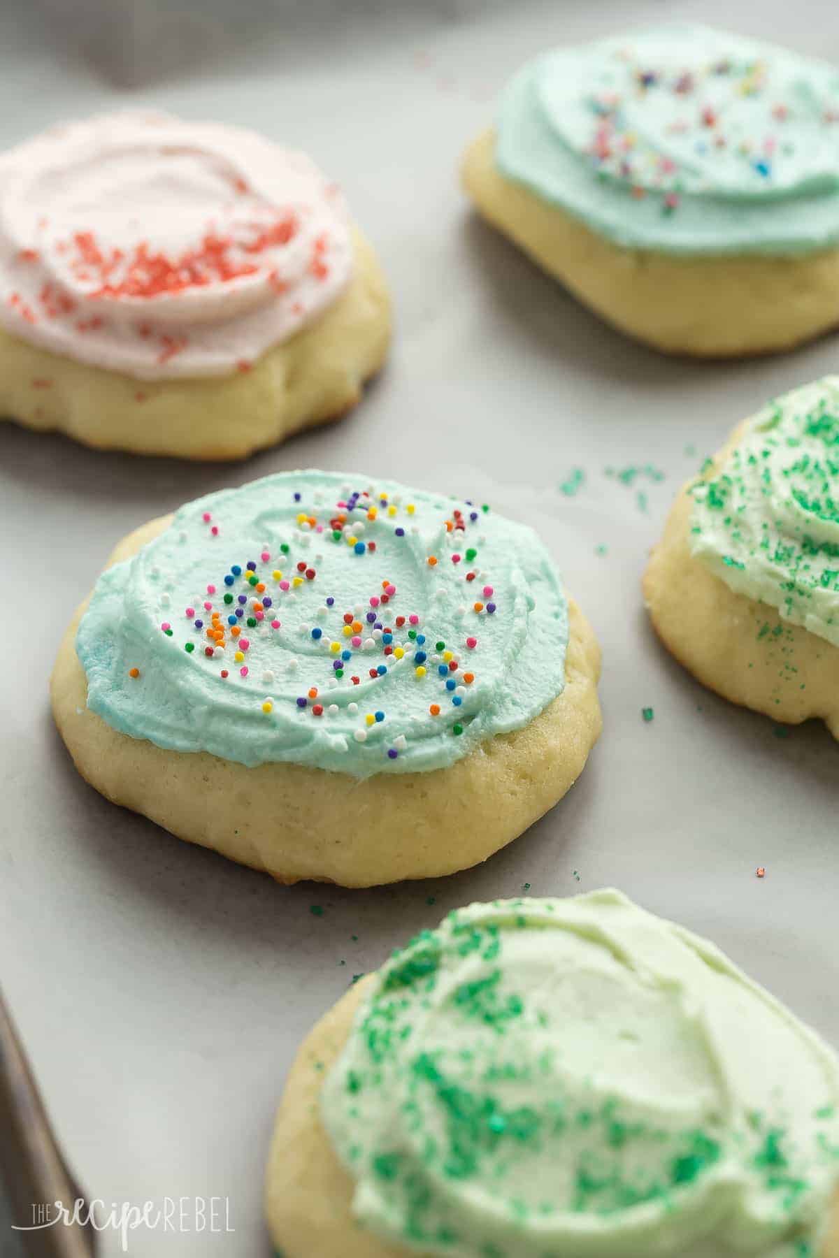 sour cream cookies on parchment paper close up with blue frosting and sprinkles