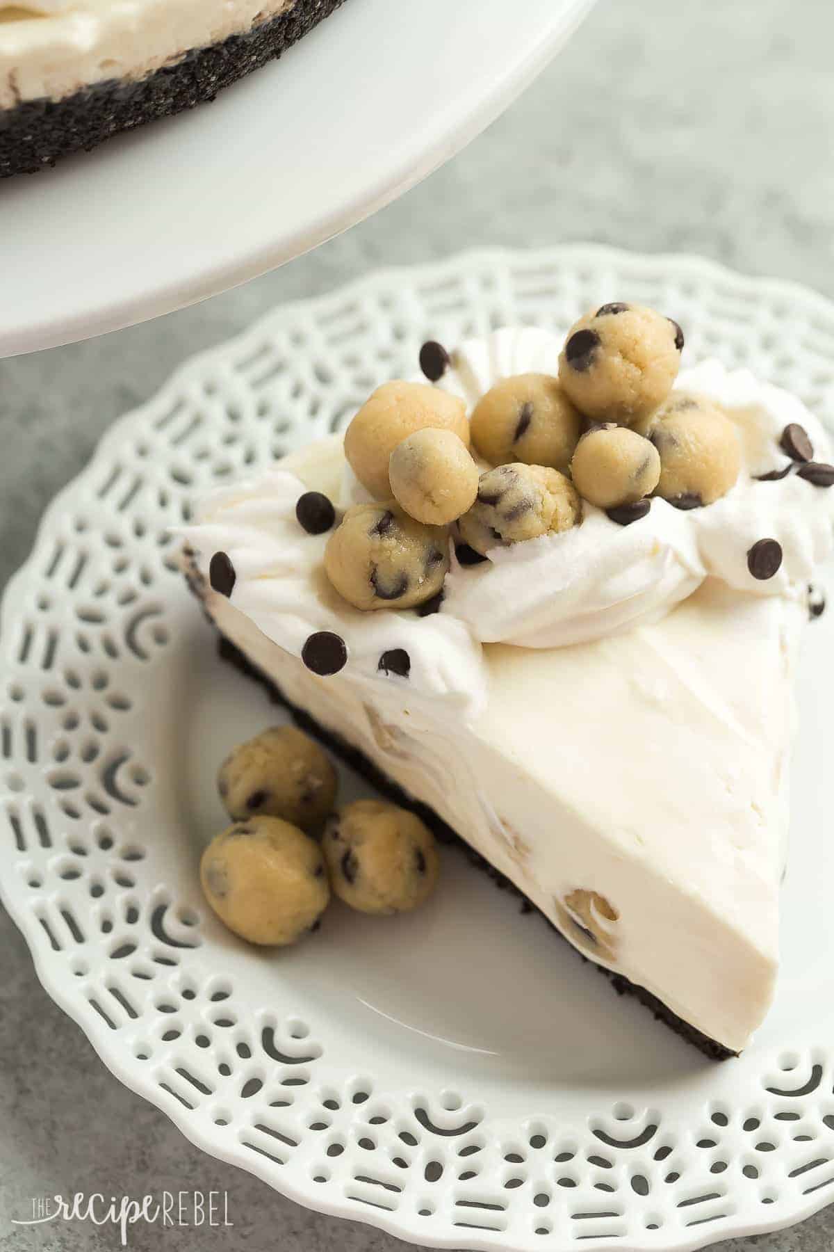 no bake cookie dough cheesecake on white plate with whipped cream and cookie dough balls