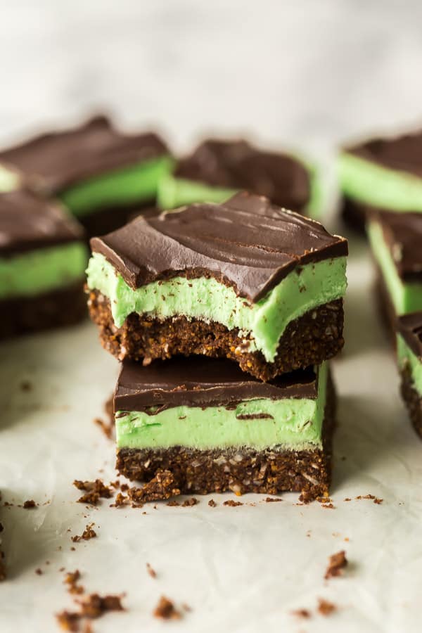 These No Bake Mint Chocolate Bars are made with a no bake graham cracker crust and topped with a creamy mint filling and chocolate ganache! #mint #chocolate #bars #christmas #baking two mint bars stacked with a bite taken out of the top bar