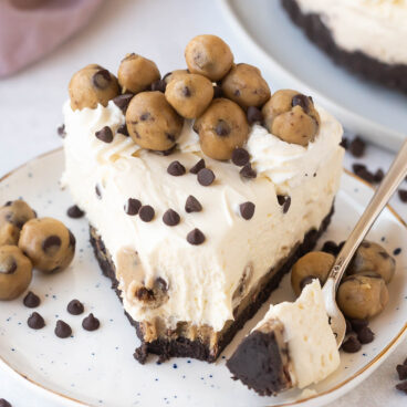 one piece of cookie dough cheesecake with bite missing.