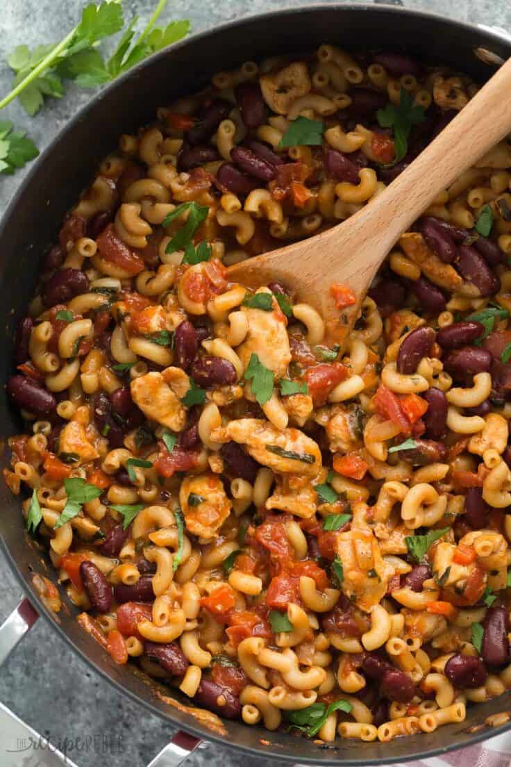 one pot bbq chicken chili mac in black pot with wooden spoon stuck in