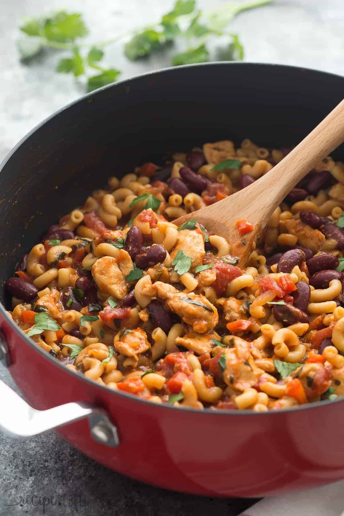 one pot bbq chicken chili mac in red pan with wooden spoon stuck in